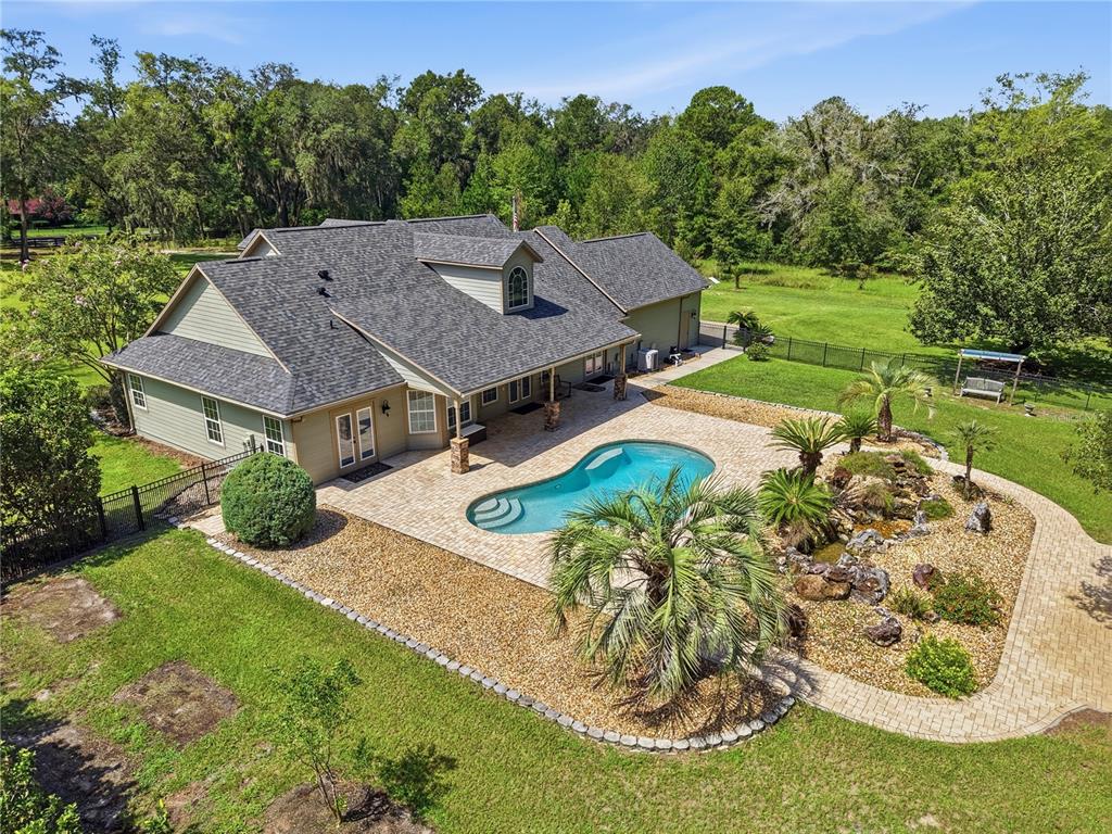 An aerial view of a house with a swimming pool, stone patio, and landscaped yard — 21158 NW COUNTY ROAD 2054, ALACHUA, FL