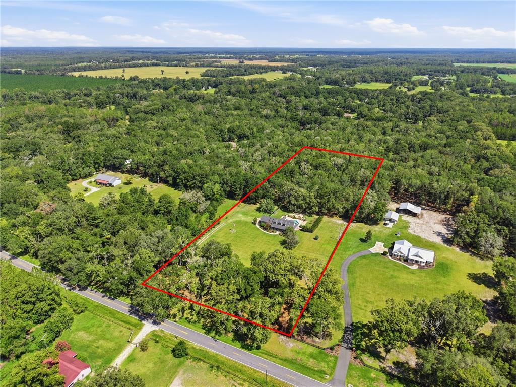 An aerial view shows a house with a pool situated on a large, wooded lot — 21158 NW COUNTY ROAD 2054, ALACHUA, FL