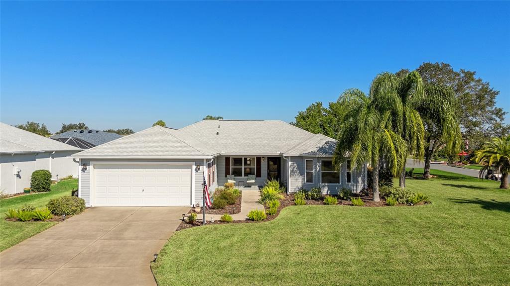 A single-story house with light gray siding, a two-car garage, and a palm tree — 3073 RIVERDALE ROAD, THE VILLAGES, FL