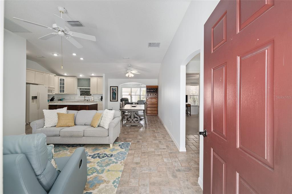 A view from an open red front door into a living room with tile floors — 3073 RIVERDALE ROAD, THE VILLAGES, FL