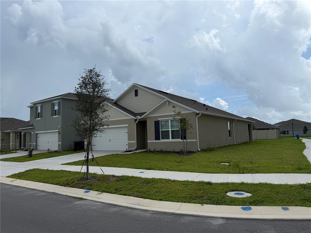 A tan, single-story suburban house with a two-car garage and a large side yard — 3307 WYNWOOD FOREST DRIVE, OCOEE, FL