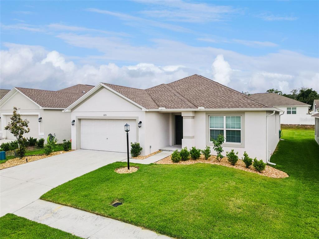 A single-story suburban house with a white stucco exterior, a two-car garage, and a lawn — 1225 PINTAIL PLACE, LAKELAND, FL