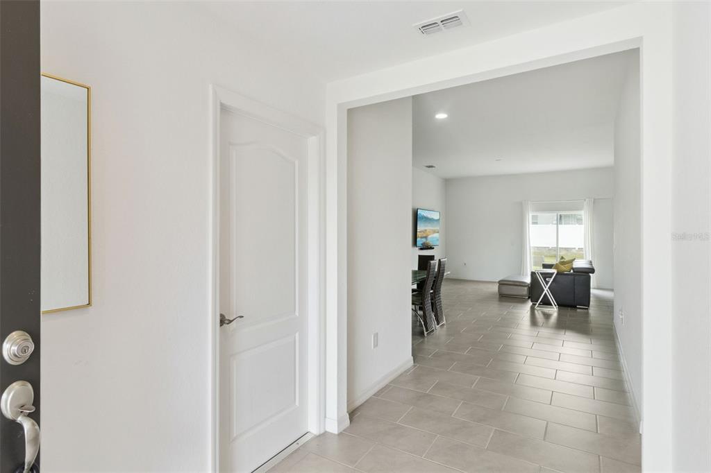 A view from an entryway looking into a tiled living area with a dining set — 1225 PINTAIL PLACE, LAKELAND, FL