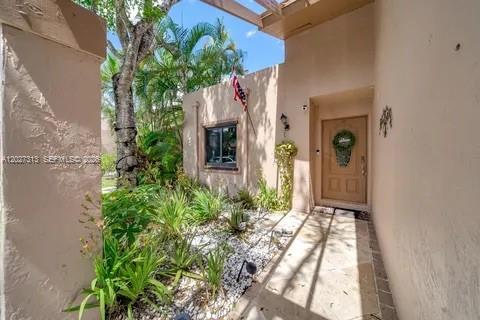 An exterior view of a tan stucco home entrance with a small garden and walkway — 36 Chestnut Cir, # 36, Cooper City FL 33026, COOPER CITY, FL