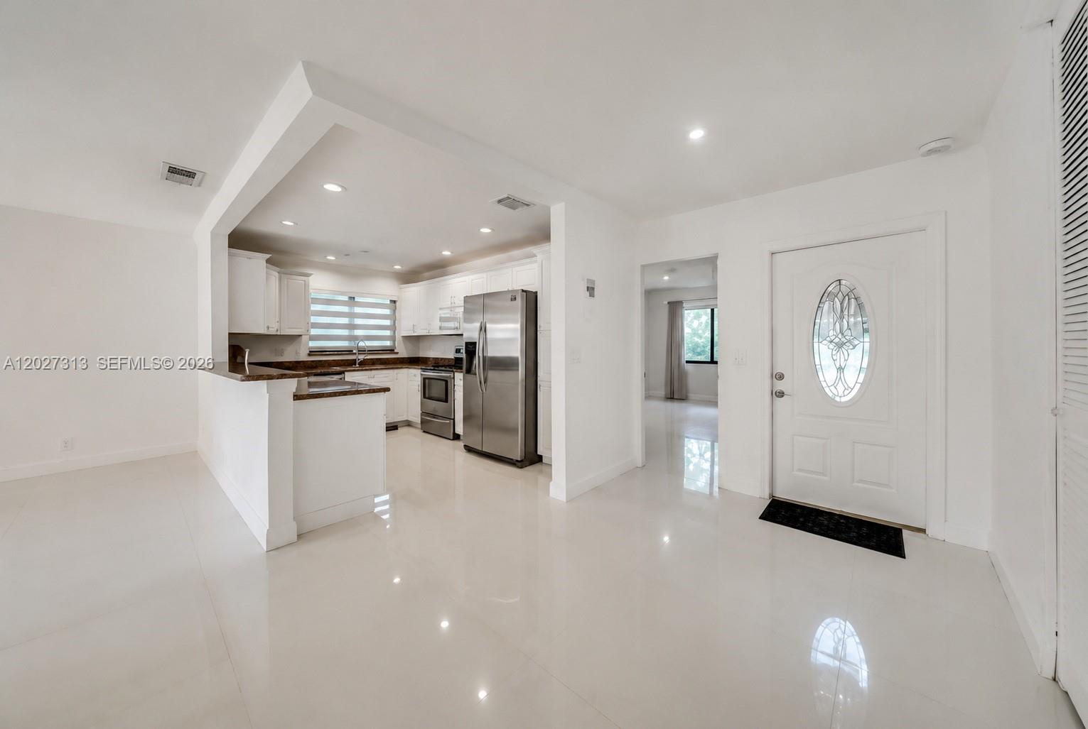 A bright kitchen with white cabinets and stainless steel appliances opens into a tiled entryway — 36 Chestnut Cir, # 36, Cooper City FL 33026, COOPER CITY, FL