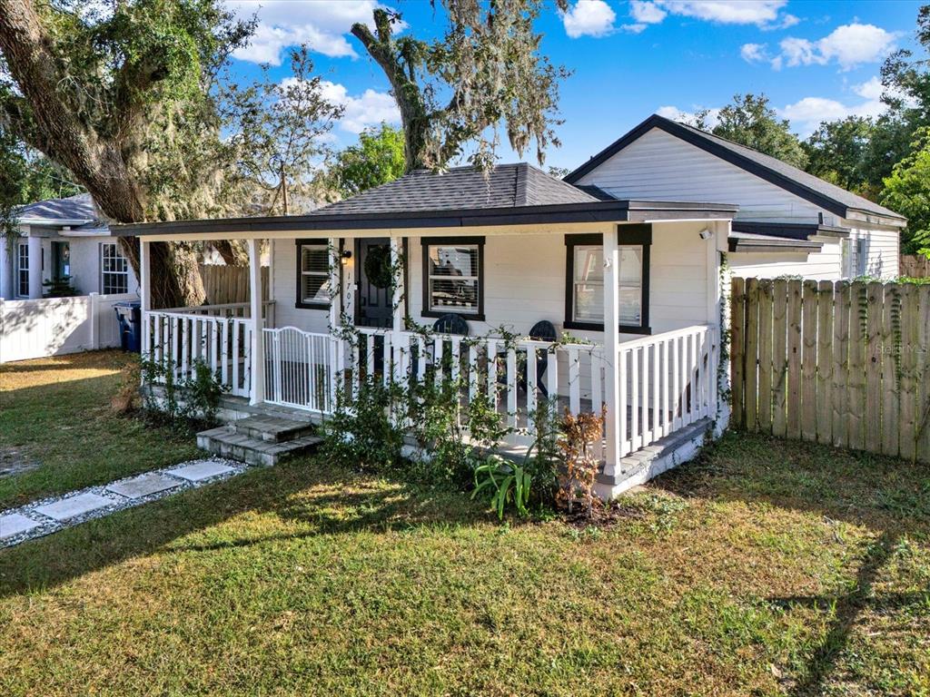 A white house with a covered front porch and black window trim sits on grass — 1707 E NEW ORLEANS AVENUE, TAMPA, FL