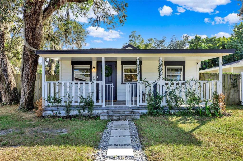 A white single-story house features a covered front porch with a white railing and walkway — 1707 E NEW ORLEANS AVENUE, TAMPA, FL