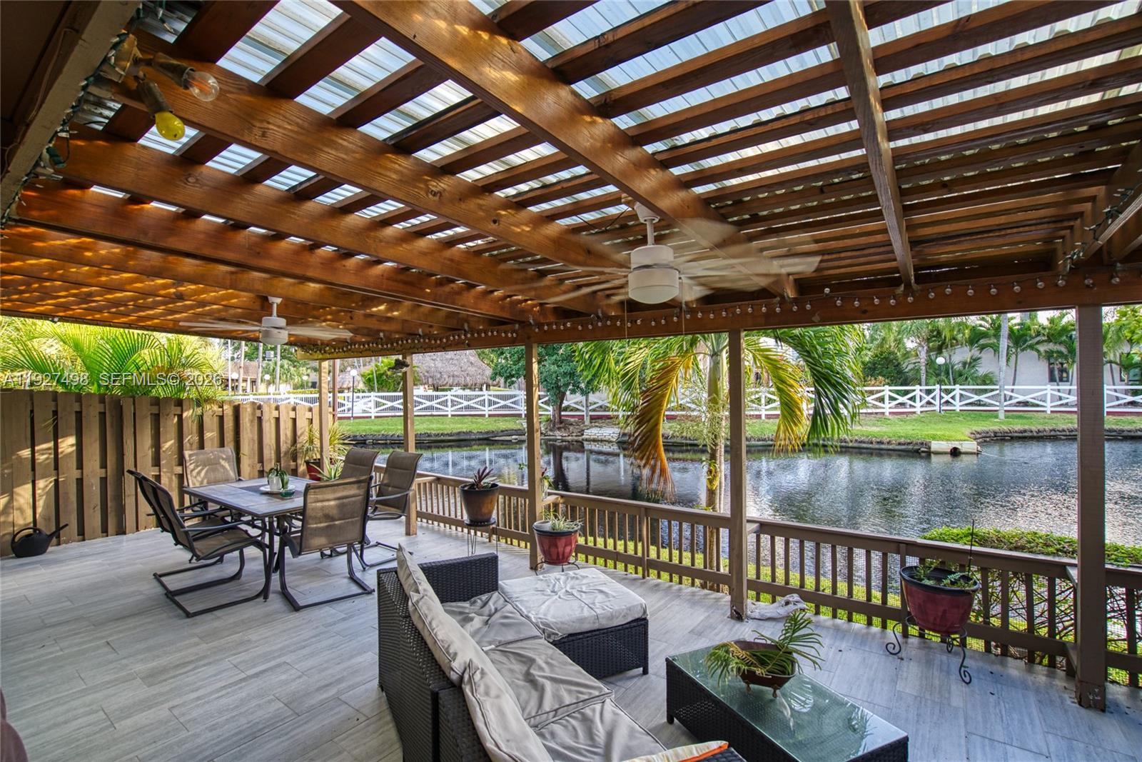 A covered outdoor patio features a wooden pergola, dining set, and sofa overlooking a canal — 2669 S Parkview Dr, Hallandale Beach FL 33009, HALLANDALE BEACH, FL
