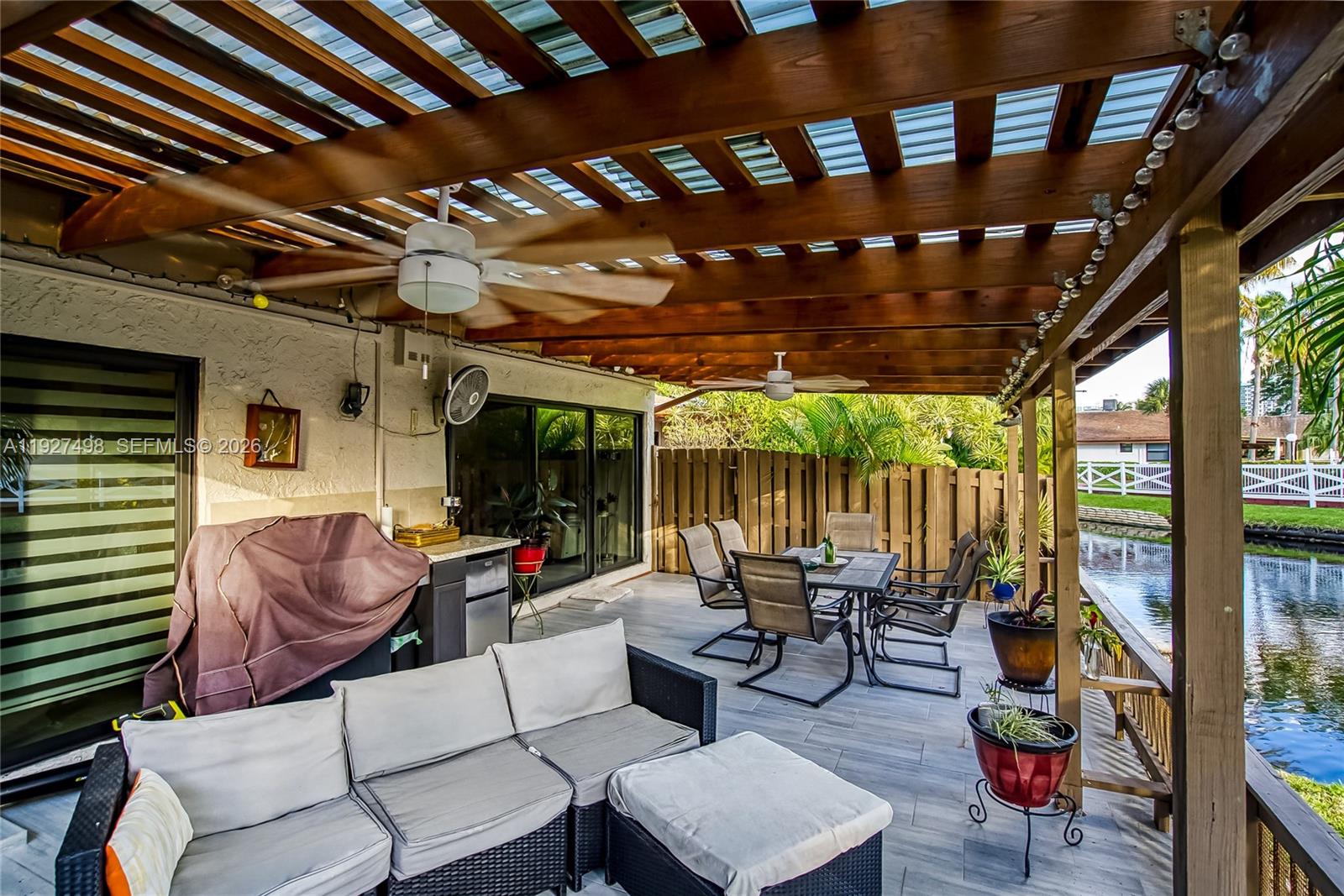 A covered outdoor patio features a dining set, sofa, grill, and ceiling fans by a canal — 2669 S Parkview Dr, Hallandale Beach FL 33009, HALLANDALE BEACH, FL