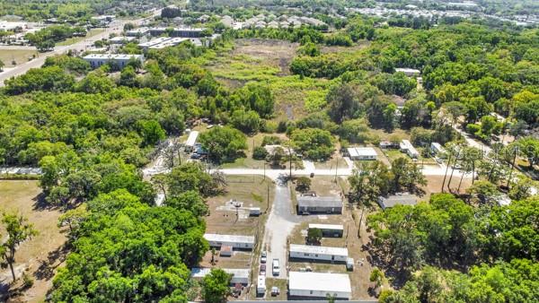 An aerial view shows several mobile homes situated on a wooded lot with gravel driveways — 8333 EMMONS AVENUE, NEW PORT RICHEY, FL