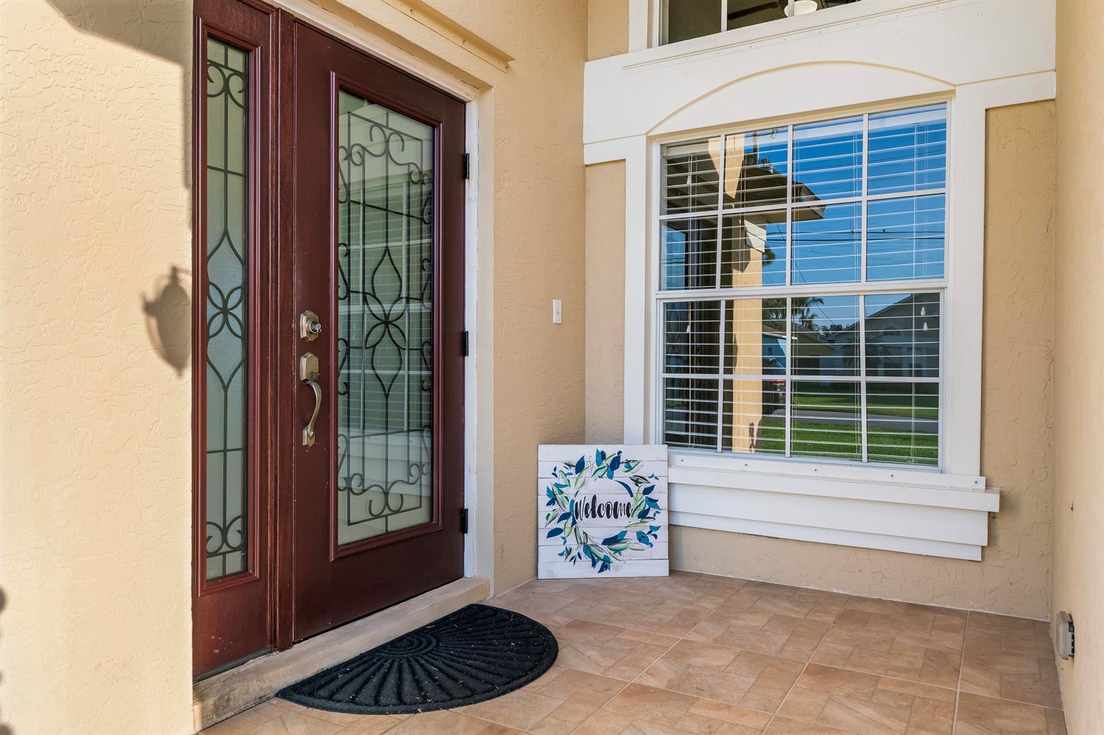 A front porch features a dark wood door with glass inserts and a welcome sign — 6118 Pompano Street, Jupiter FL 33458, JUPITER, FL