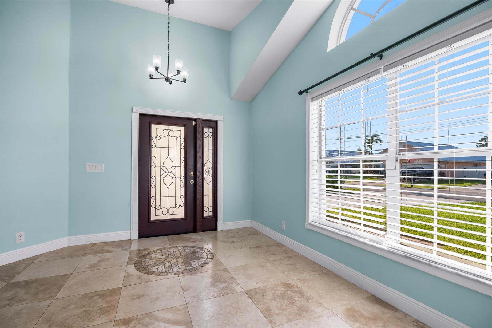 An entryway with light blue walls, tile flooring, a dark front door, and a large window — 6118 Pompano Street, Jupiter FL 33458, JUPITER, FL