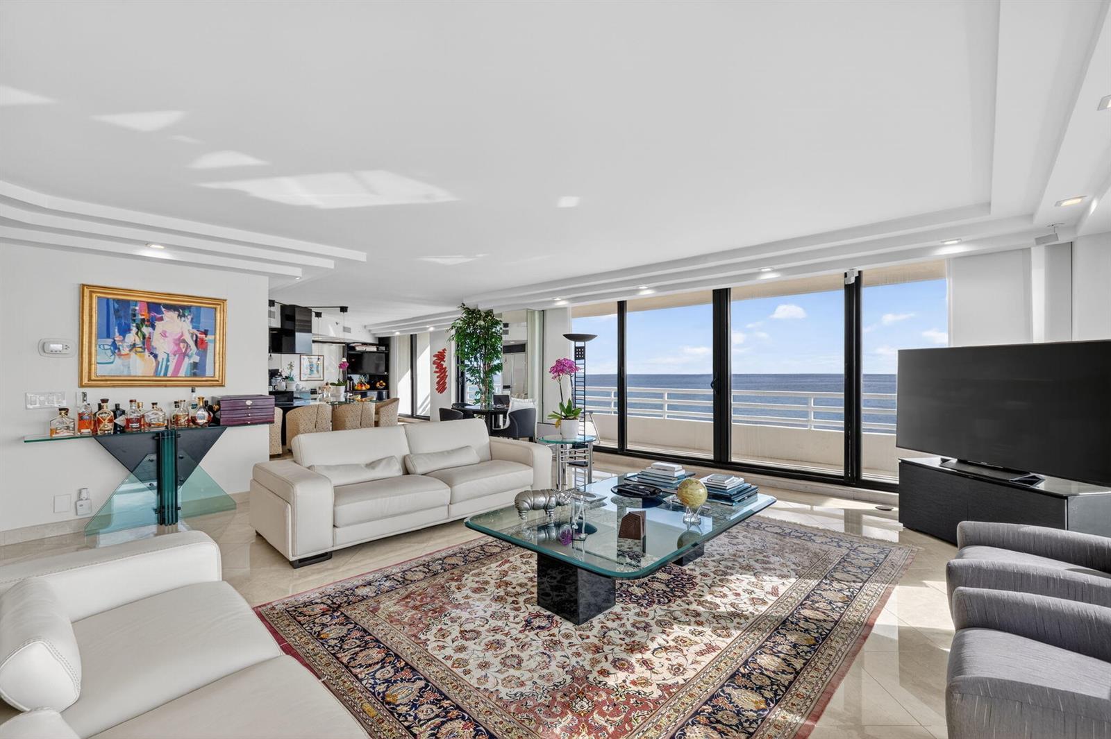 A bright living room features white leather sofas, a glass coffee table, and ocean views — 1500 S Ocean Boulevard # 606, Boca Raton FL 33432, BOCA RATON, FL
