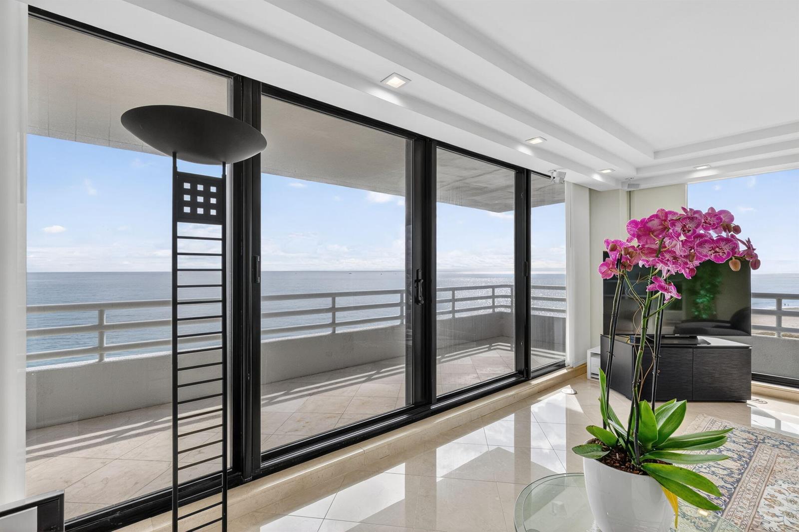 A bright living room features large sliding glass doors opening to a balcony overlooking the ocean — 1500 S Ocean Boulevard # 606, Boca Raton FL 33432, BOCA RATON, FL