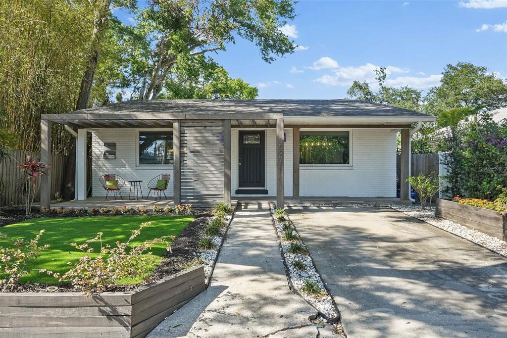 A white brick house features a wooden pergola, a front porch, and a concrete driveway — 3027 BURLINGTON AVENUE N, ST PETERSBURG, FL