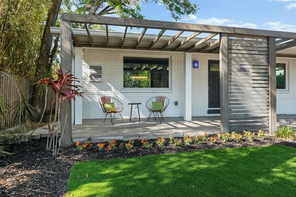 A white brick house exterior features a wooden pergola, a front porch, and two chairs — 3027 BURLINGTON AVENUE N, ST PETERSBURG, FL