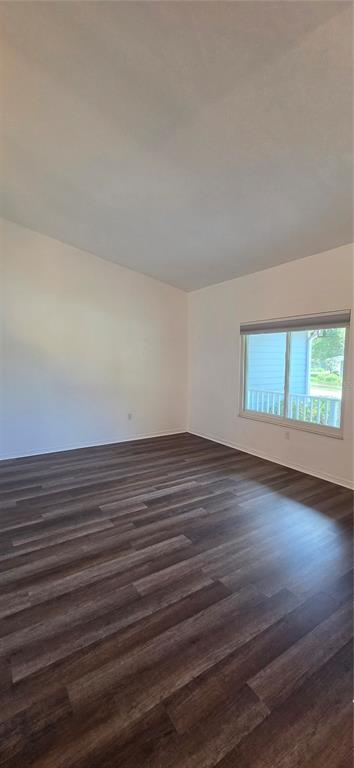 An empty room with dark wood-look flooring, white walls, and a single window — 1419 NW 89TH TERRACE, GAINESVILLE, FL