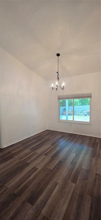 An empty dining room features wood-look flooring, white walls, and a hanging chandelier — 1419 NW 89TH TERRACE, GAINESVILLE, FL