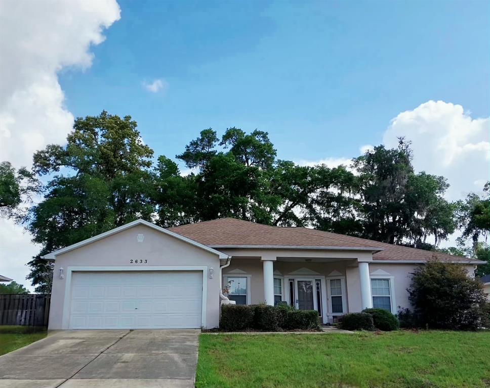 A single-story house with a two-car garage, light-colored stucco exterior, and a large front lawn — 2633 NE 27TH STREET, OCALA, FL