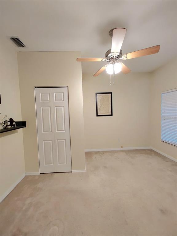 A bedroom with beige carpet, a ceiling fan, a white closet door, and a framed map — 2633 NE 27TH STREET, OCALA, FL