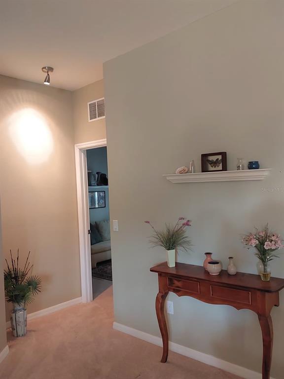 A hallway features a wooden console table, a wall shelf, and a doorway leading inside — 2633 NE 27TH STREET, OCALA, FL