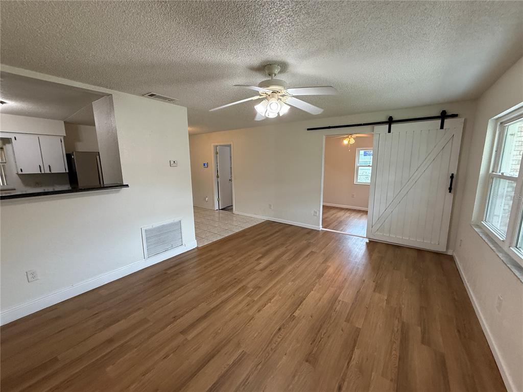 A living room features wood-look flooring, a ceiling fan, and a white sliding barn door — 202 YALE DRIVE, SANFORD, FL