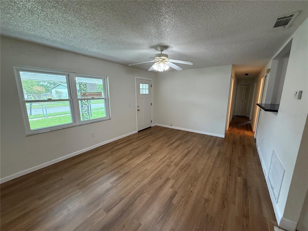 A living room features light-colored walls, wood-look flooring, a ceiling fan, and a front door — 202 YALE DRIVE, SANFORD, FL