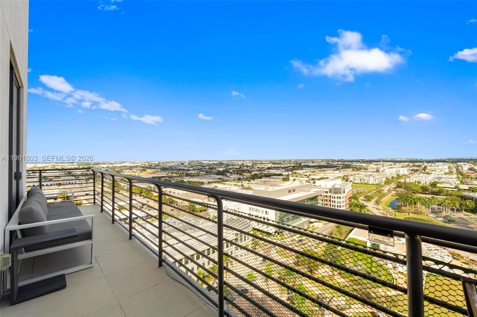 A high-rise balcony features a metal railing, mesh screen, and a gray outdoor sofa — 5350 NW 84th Ave # 2013, Doral FL 33166, DORAL, FL