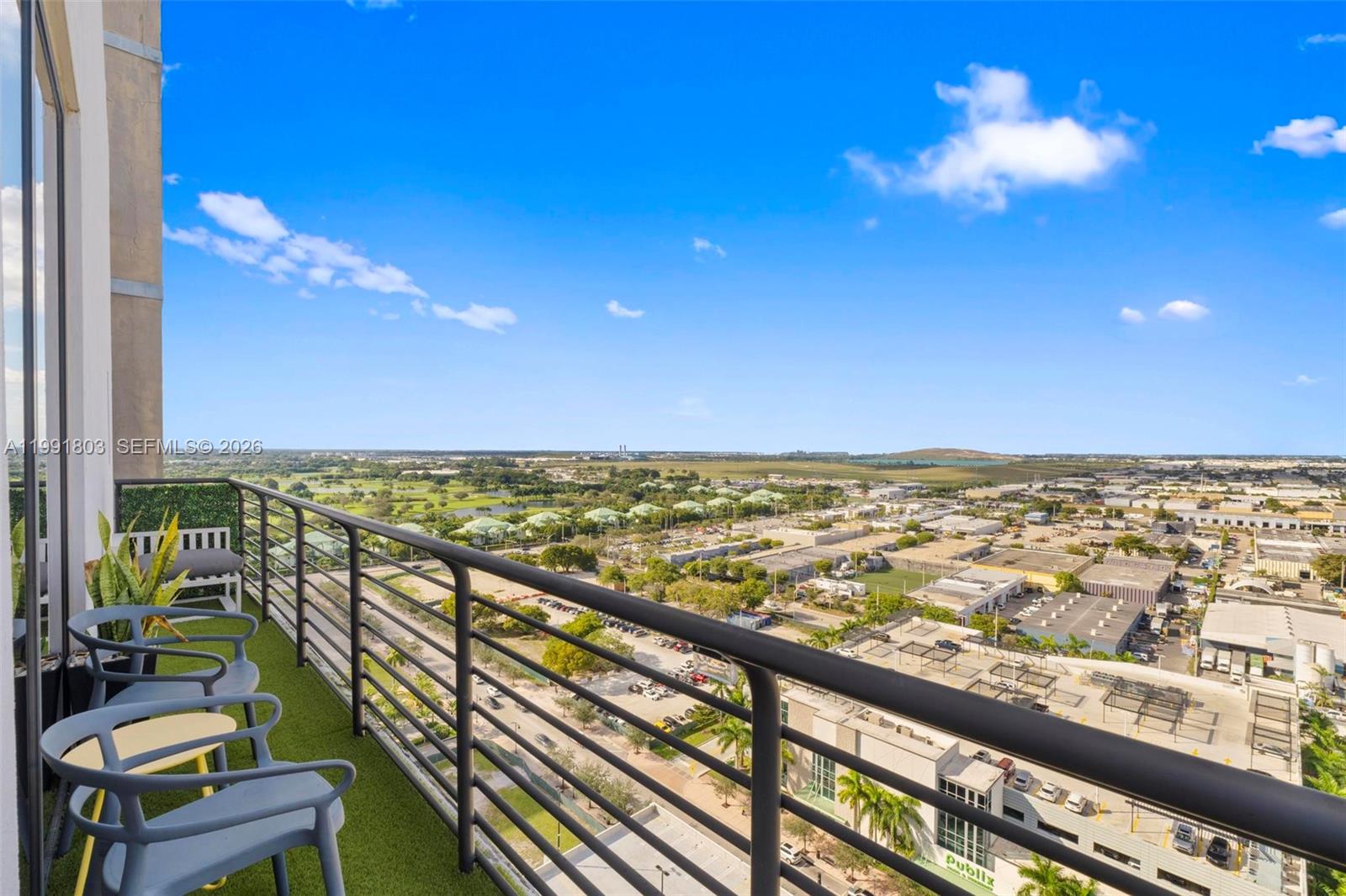 A high-rise balcony with artificial turf, patio chairs, and a view of a suburban landscape — 5350 NW 84th Ave # 2013, Doral FL 33166, DORAL, FL