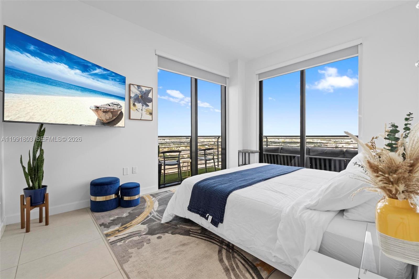 A bedroom features a bed, a wall-mounted television, and floor-to-ceiling windows with balcony access — 5350 NW 84th Ave # 2013, Doral FL 33166, DORAL, FL