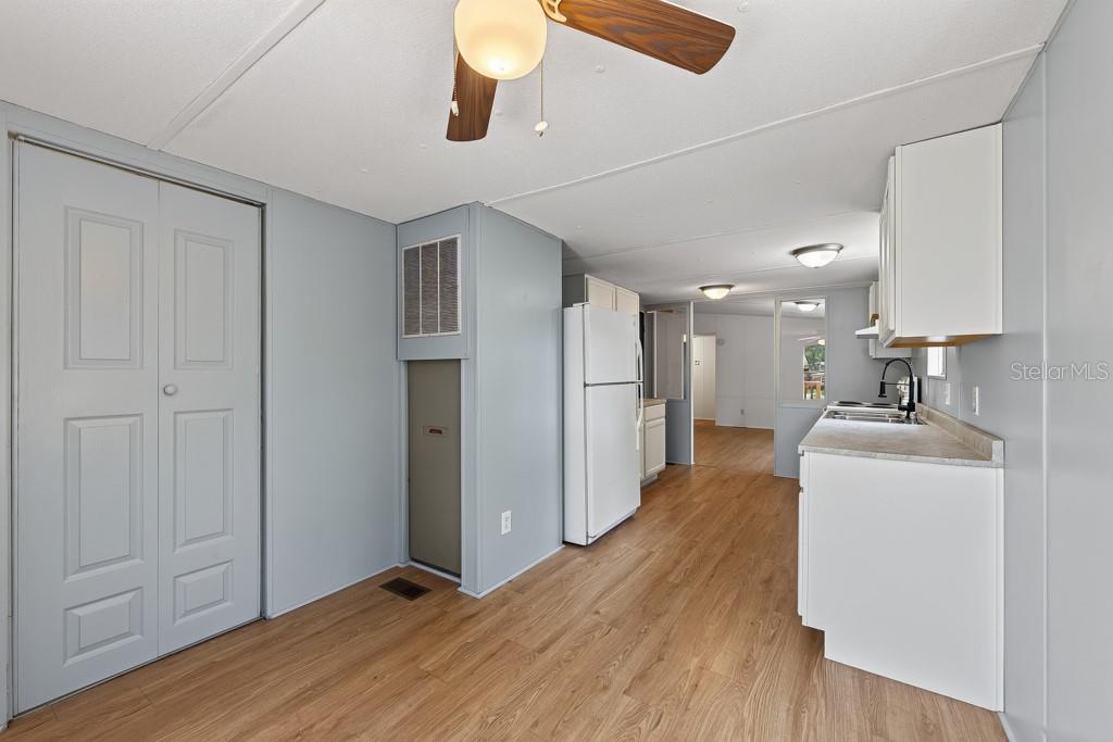 A kitchen with light wood-look flooring, white cabinets, and a white refrigerator — 11711 TUCKER ROAD, RIVERVIEW, FL