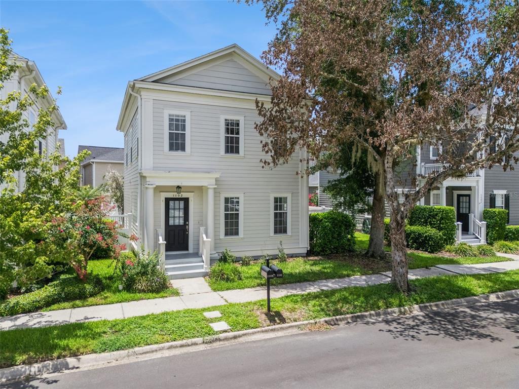 A two-story light-colored house with a front porch and a black door — 1102 GOLDENASTER COURT, CELEBRATION, FL