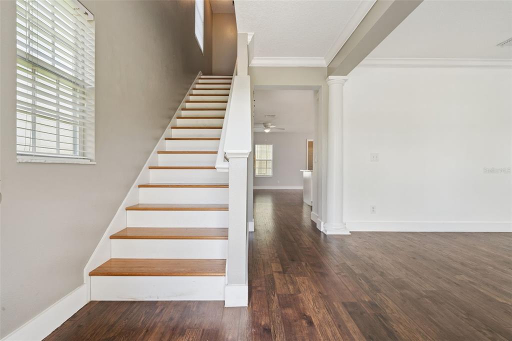 A staircase with wooden treads and white risers stands beside a columned entryway — 1102 GOLDENASTER COURT, CELEBRATION, FL