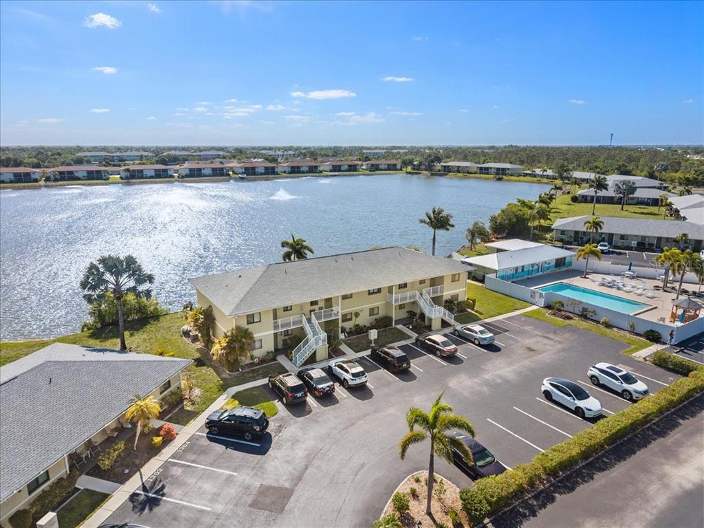 An aerial view shows a two-story apartment building with a parking lot and swimming pool — 25225 RAMPART BOULEVARD UNIT 1207, PUNTA GORDA, FL