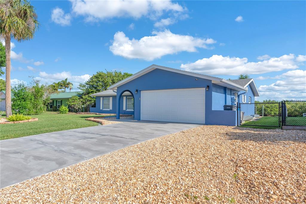 A blue single-story house with a white garage door and a gravel driveway — 911 SILVER PALM WAY, APOLLO BEACH, FL