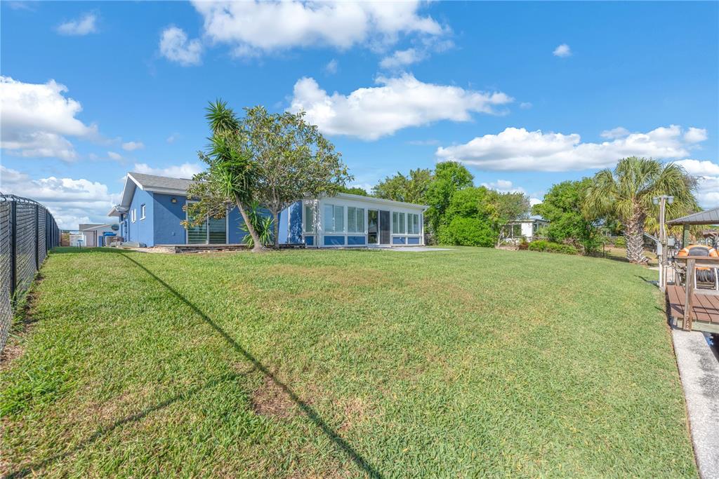 A blue house with a sunroom sits on a grassy lawn next to a canal — 911 SILVER PALM WAY, APOLLO BEACH, FL