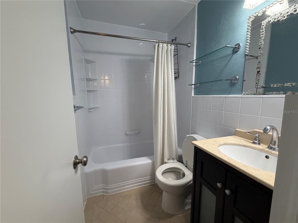 A bathroom features a white tiled tub-shower combo, a toilet, and a dark vanity — 701 SW 28TH STREET, GAINESVILLE, FL