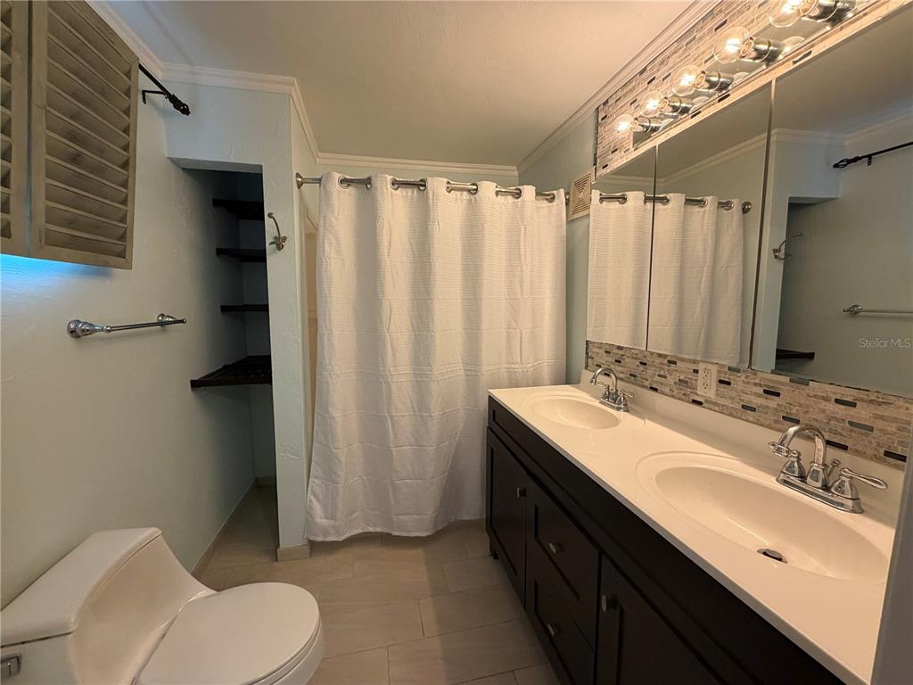 A bathroom features a double vanity with dark cabinets, a toilet, and a shower curtain — 701 SW 28TH STREET, GAINESVILLE, FL