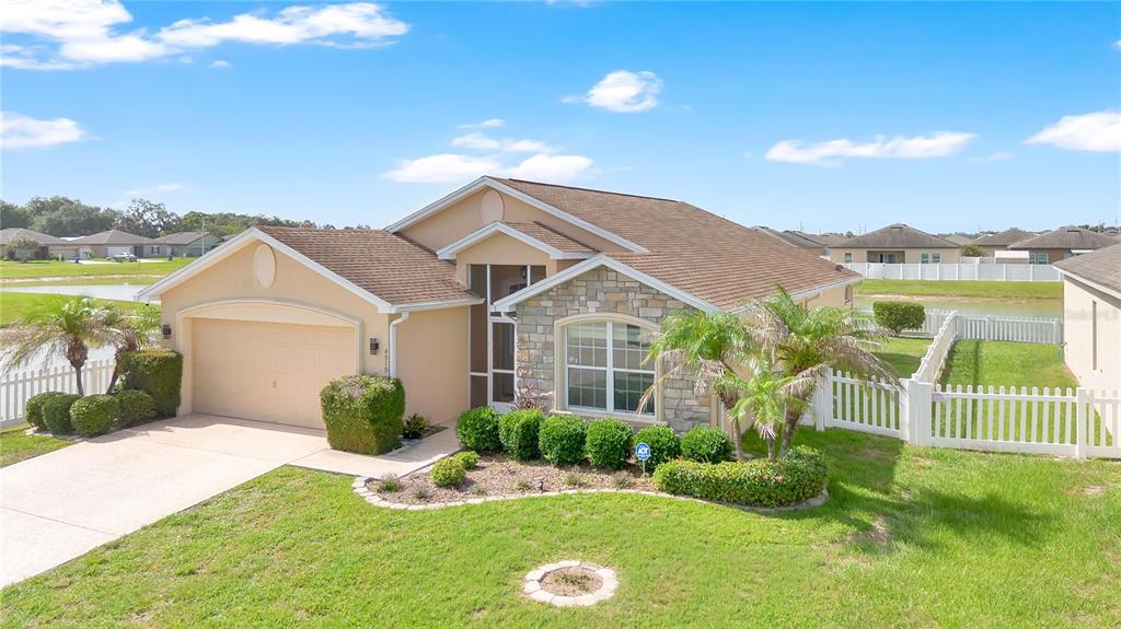 A single-story suburban house with a tan stucco exterior, stone accents, and a two-car garage — 4919 ST JAMES DRIVE, WINTER HAVEN, FL