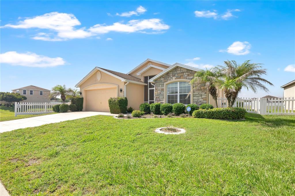A single-story house with a stone facade, a two-car garage, and a white picket fence — 4919 ST JAMES DRIVE, WINTER HAVEN, FL