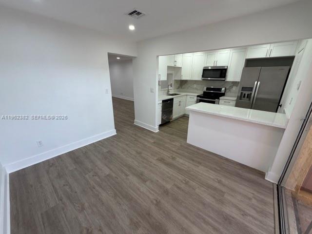 A kitchen with white cabinets and stainless steel appliances opens to a wood-floored dining area — 13725 SW 84th St # C, Miami FL 33183, MIAMI, FL