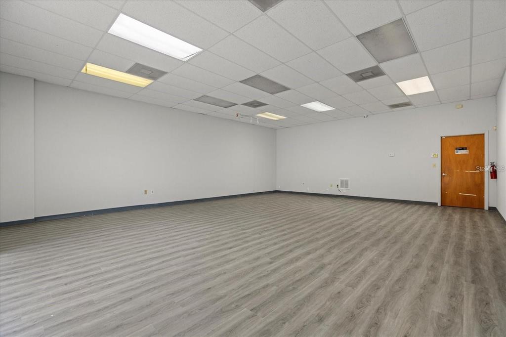 An empty office space with gray wood-look flooring, white walls, and a drop ceiling — 1650 TROPIC PARK DRIVE UNIT 1650, SANFORD, FL