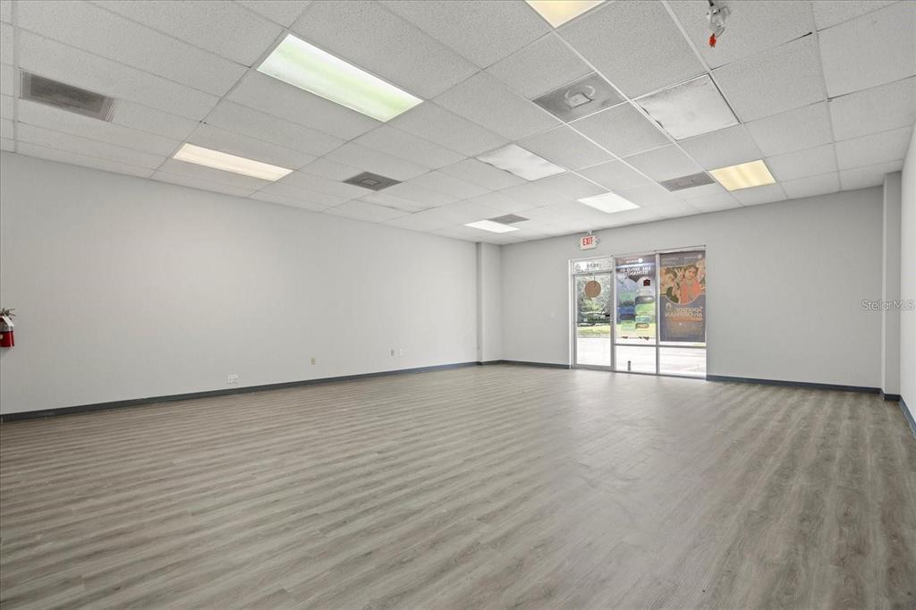 An empty commercial space features light wood-look flooring, white walls, and a drop ceiling — 1650 TROPIC PARK DRIVE UNIT 1650, SANFORD, FL
