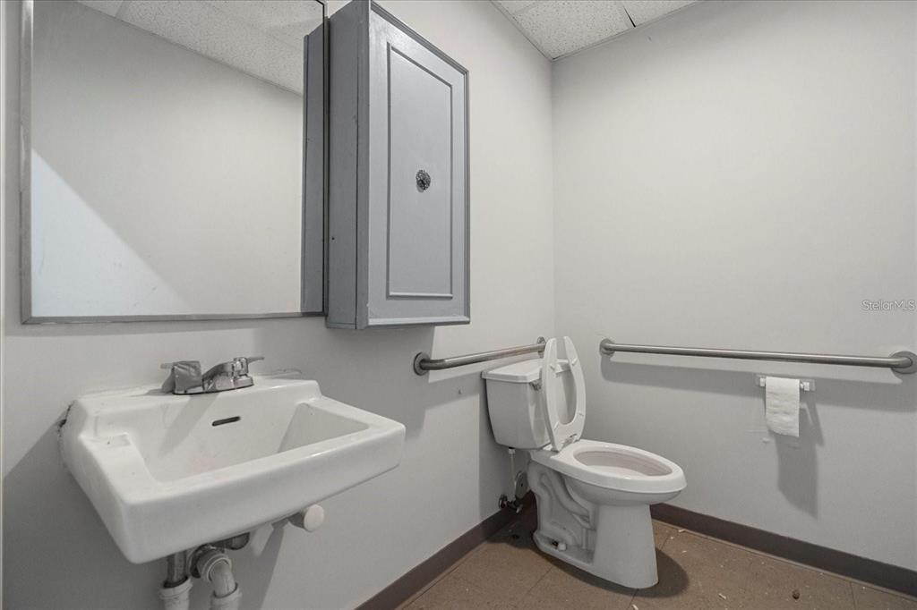 A small, utilitarian bathroom features a wall-mounted sink, a toilet, and grab bars — 1650 TROPIC PARK DRIVE UNIT 1650, SANFORD, FL