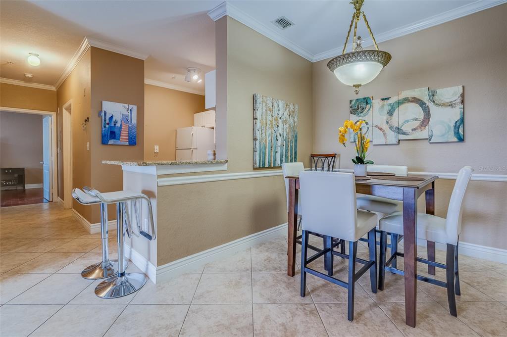 A dining area with a breakfast bar, tile flooring, and a pendant light fixture — 2705 VIA MURANO UNIT 136, CLEARWATER, FL