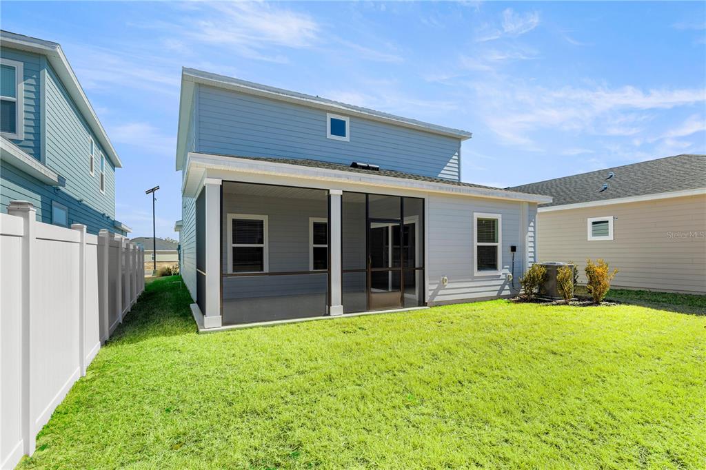 The exterior rear view of a two-story house features a screened-in porch and lawn — 8708 SW 67TH TERRACE, OCALA, FL