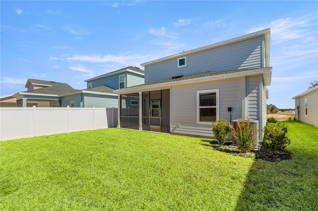 The backyard features a green lawn, a screened-in patio, and a two-story light blue house — 8708 SW 67TH TERRACE, OCALA, FL