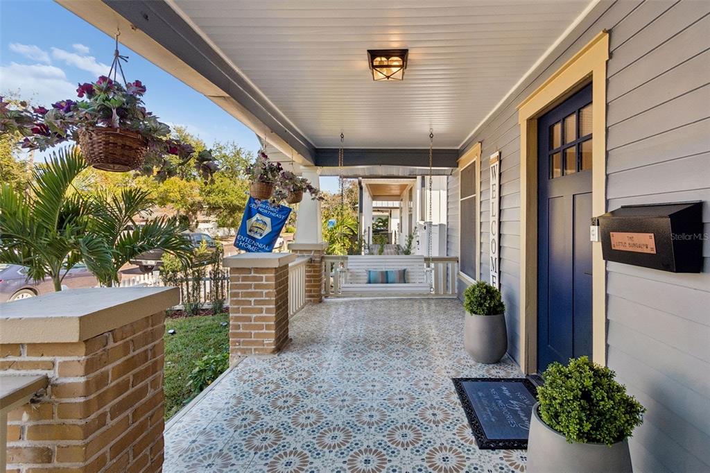 A covered front porch features patterned tile flooring, a hanging swing, and a blue door — 322 11TH AVENUE N, ST PETERSBURG, FL