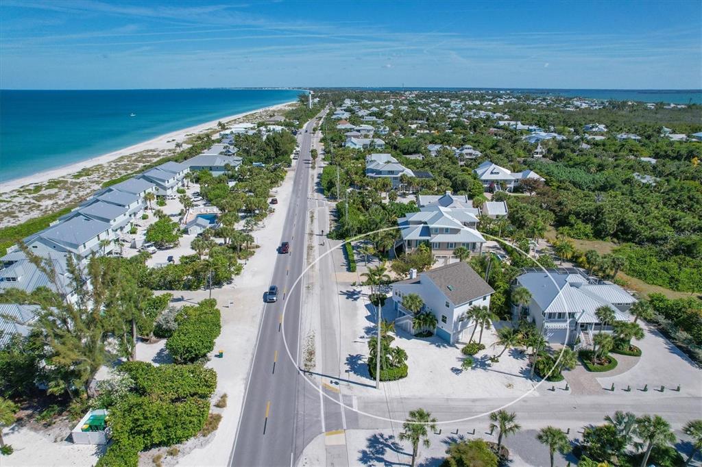An aerial view shows a coastal road lined with houses and a sandy beach nearby — 401 LAFITTE STREET, BOCA GRANDE, FL