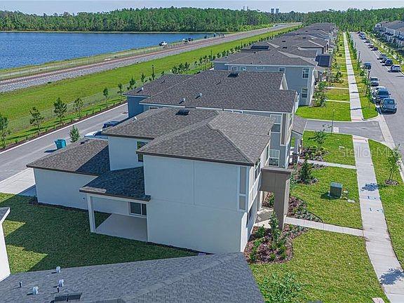 An aerial view shows a multi-story residential building with a covered patio and nearby lake — 11420 SUNSAIL AVENUE, ORLANDO, FL